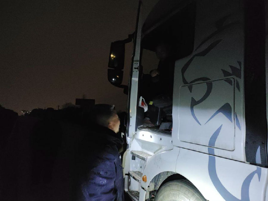 图为江湾村两委干部询问滞留货车司机情况（王梦 摄）