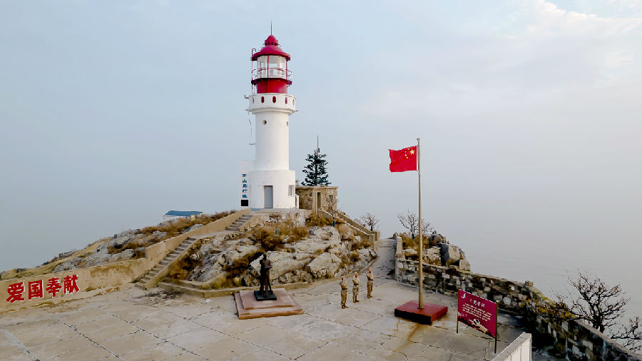 守岛民兵在现开山岛灯塔下升国旗（乔钰 摄）