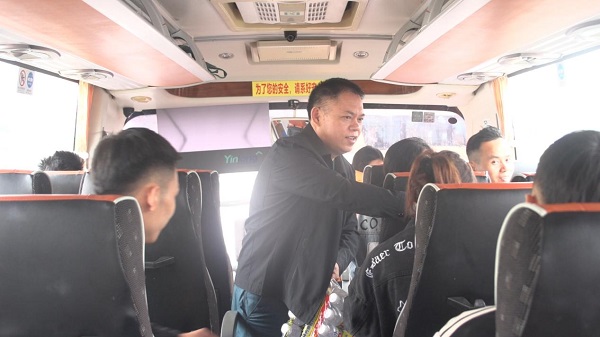 临高县人力资源服务中心副主任倪志荣为外出务工人员送上矿泉水等爱心零食。（郑天龙 摄）