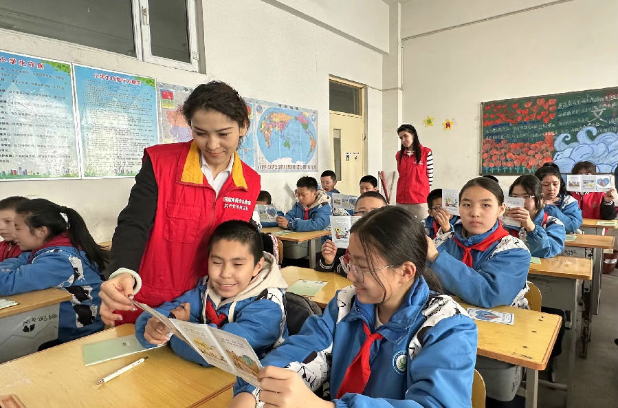 图为国网阿克苏市供电公司党员服务队为孩子讲解用电宣传画册 （邸敏 摄）