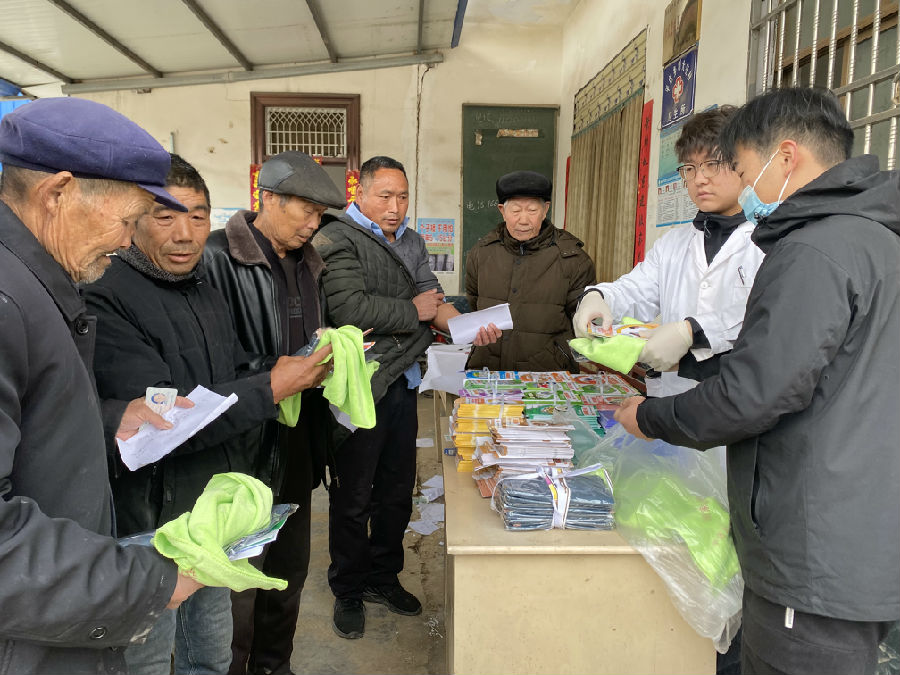 医护人员在刘大庄村卫生室体检现场给群众发放健康知识宣传手册 （赵永昌 摄）