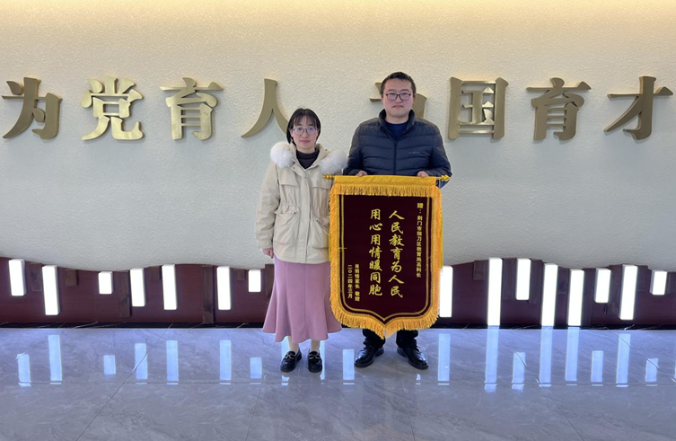 图为返乡人员肖桂芳送锦旗送给掇刀区教育局相关负责人 （简明 摄）