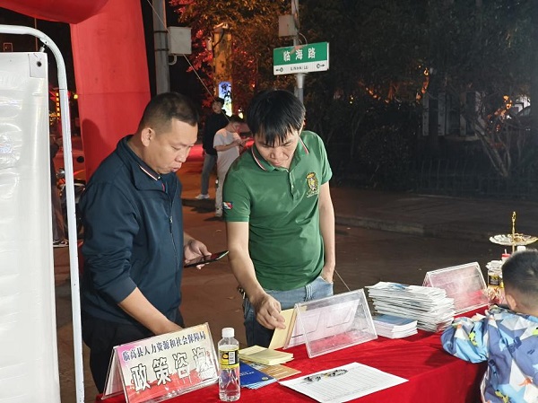 工作人员向临高县人力资源服务中心办公室主任田振龙（左一）介绍政策宣传区（颜海彪 摄）