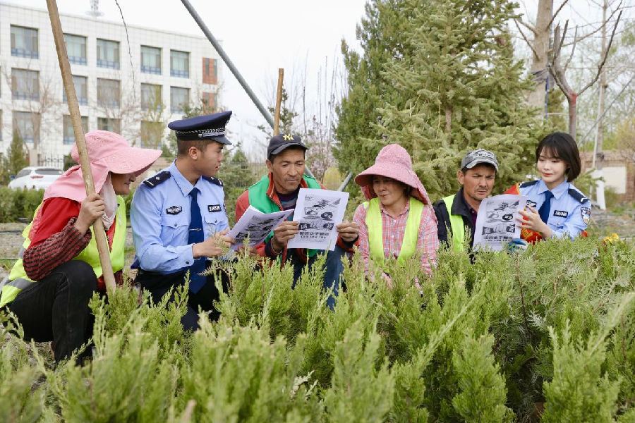 图为城镇派出所民警在给农民宣传电信诈骗和农业安全生产 （沈丹 摄）