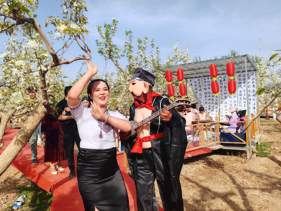 图为游人在温宿县克孜勒镇乌克铁热克村梨花园载歌载舞（ 玛依拉·阿不来提 摄）