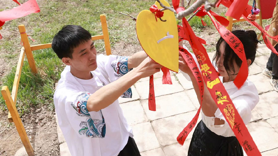 图为游客将写好的红丝带悬挂于梨树枝头（陈悠峥 摄）