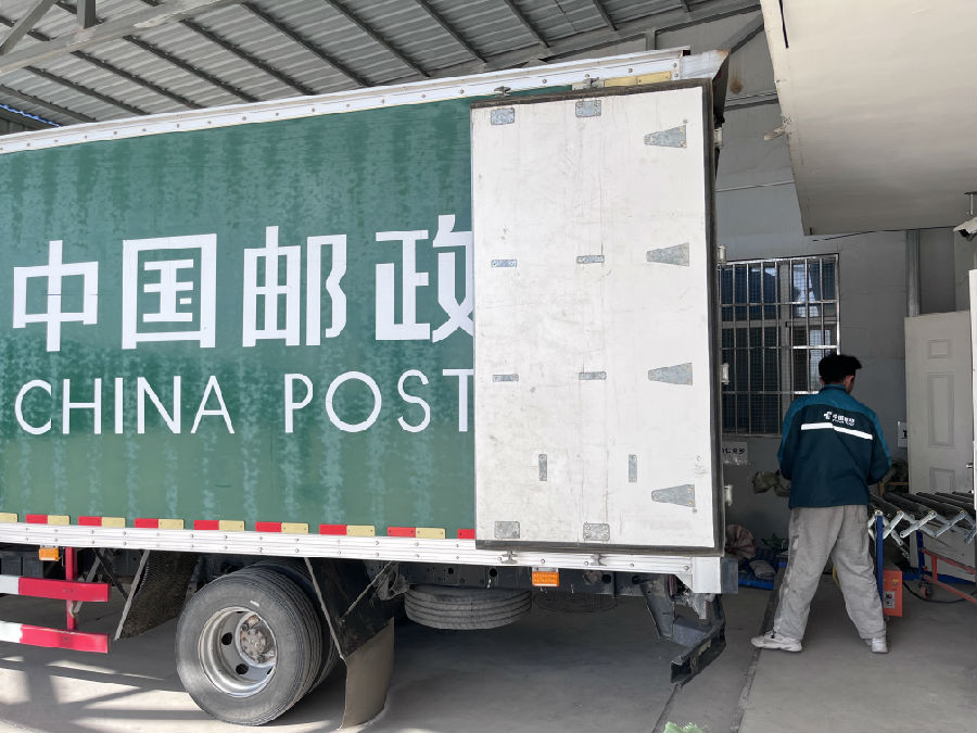 图为快递员把包裹放到传送机上(杨家佳 摄)