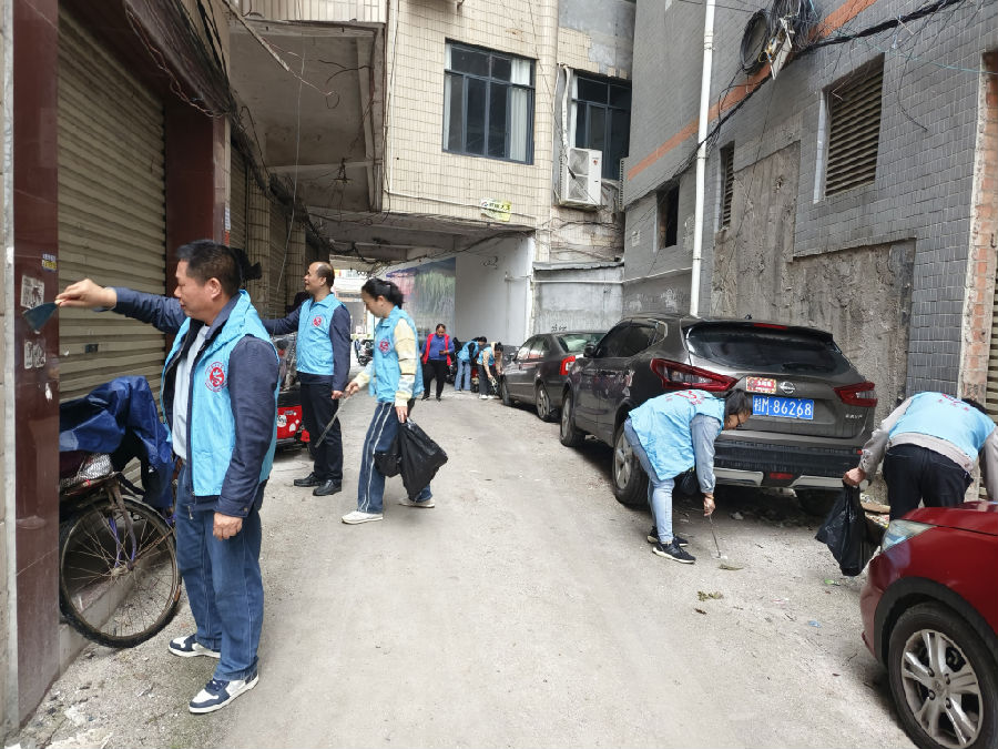 图为志愿者深入社区开展环境卫生清理活动（潘玉云 摄）