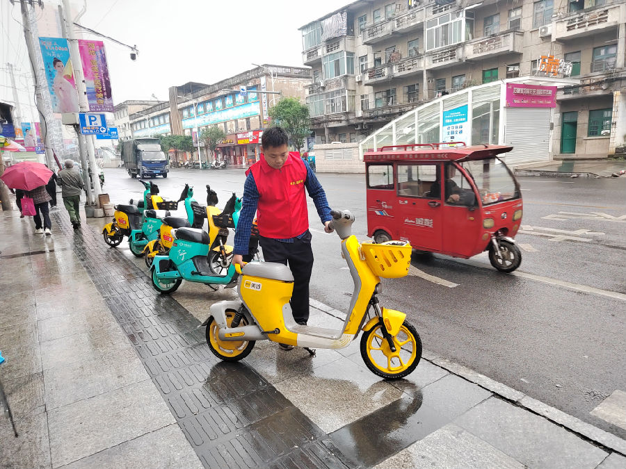 图为党员志愿者对路边乱停乱放车辆进行整治（韦峰 摄）