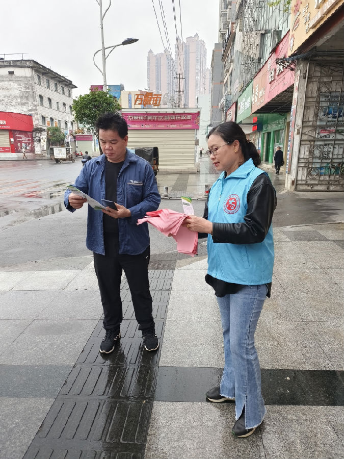 图为志愿者走上街头向市民发放文明城市创建宣传资料（覃业军 摄）