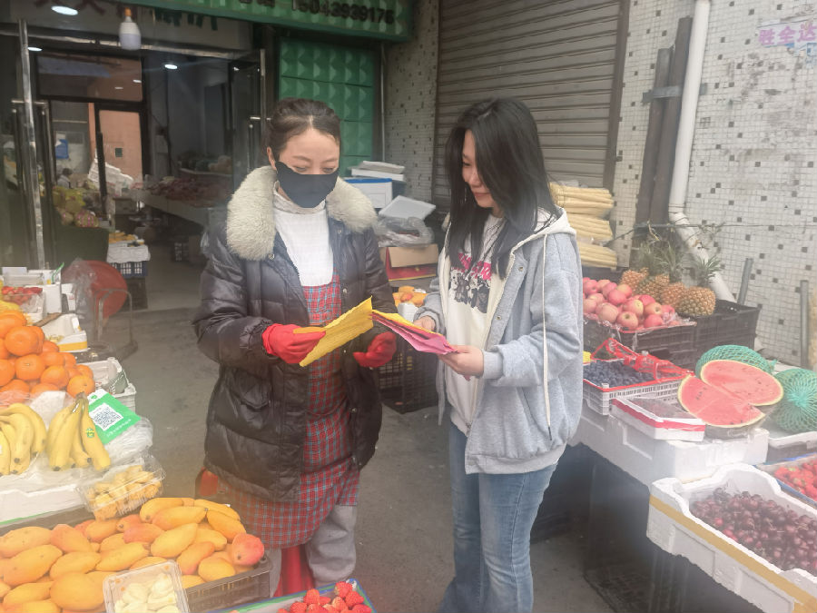 工作人员向周边商户讲解宣传内容（赵铭 摄）