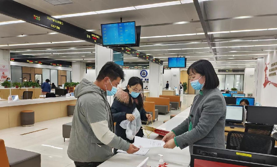 图为业务办理人员递交帮办材料（甘申轩 摄）