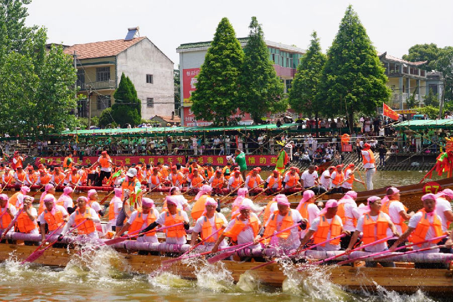 端午前夕，在黄梅县小池镇东港开阔水域，龙船队员以站姿挥桨斩浪。 （费留灿 摄）