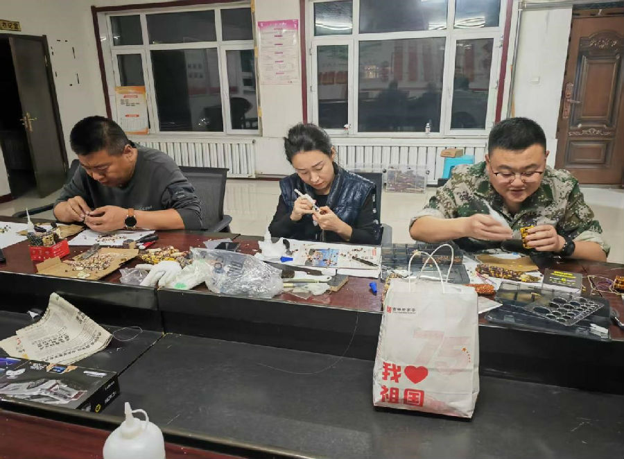 村党支部书记刘长海、村民、驻村队员共同制作玉米工艺品（张健 摄）