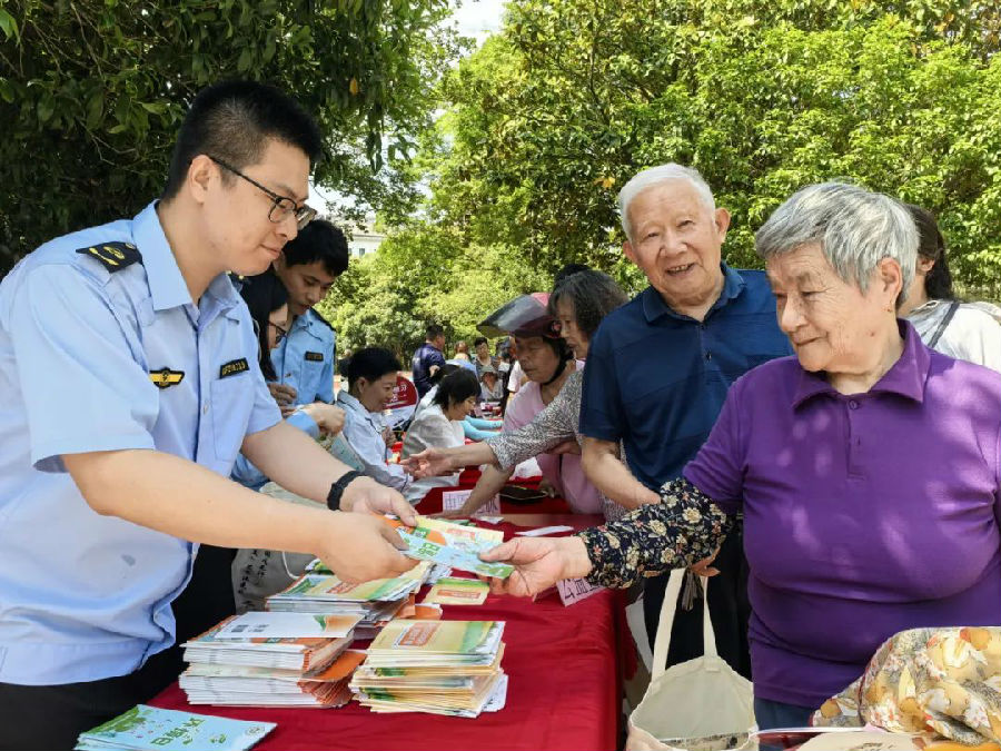 活动现场，当天工作人员将宣传画册分发给当地群众。（汪宇陆 摄）