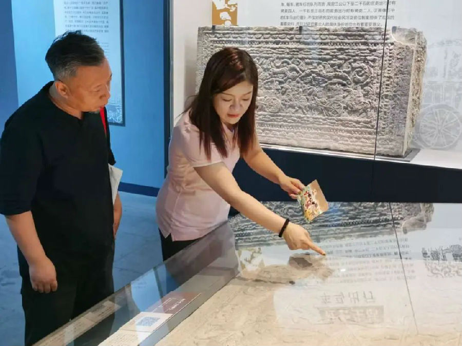 睢宁县博物馆工作人员为洪流介绍《舞乐车马图》汉画像石原石（陆纪斌 摄）