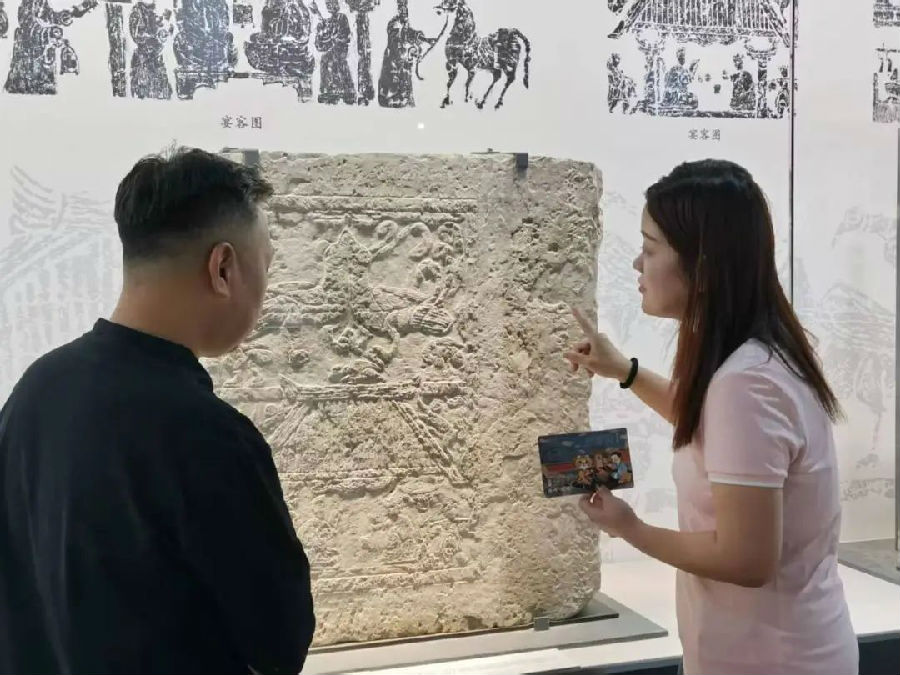 睢宁县博物馆工作人员为洪流讲解馆藏汉画像石《宴客图》内“吃烧烤”场景 （陆纪斌 摄）