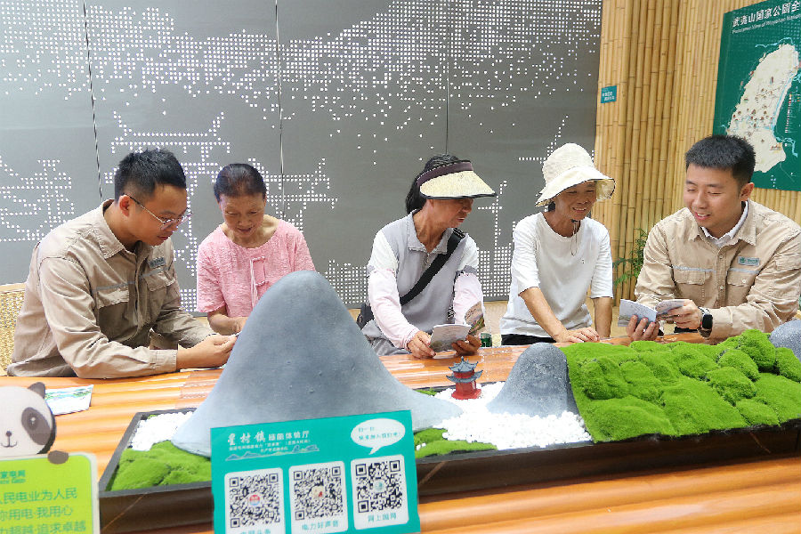 供电人员通过口袋书向游客及当地居民传播生态保护理念。（陈龙辉 摄）
