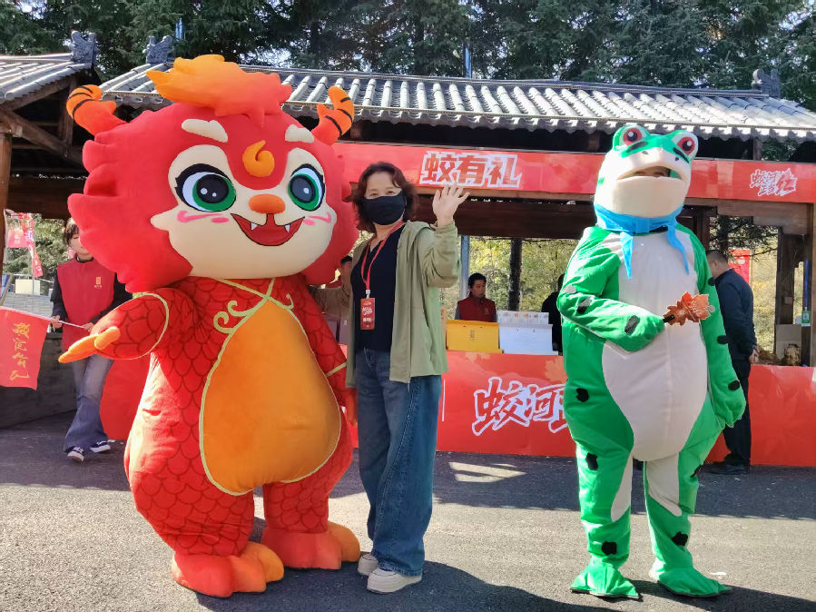 充满童趣的小蛟龙和憨态可掬的青蛙人偶与游客互动（贾云生 摄）