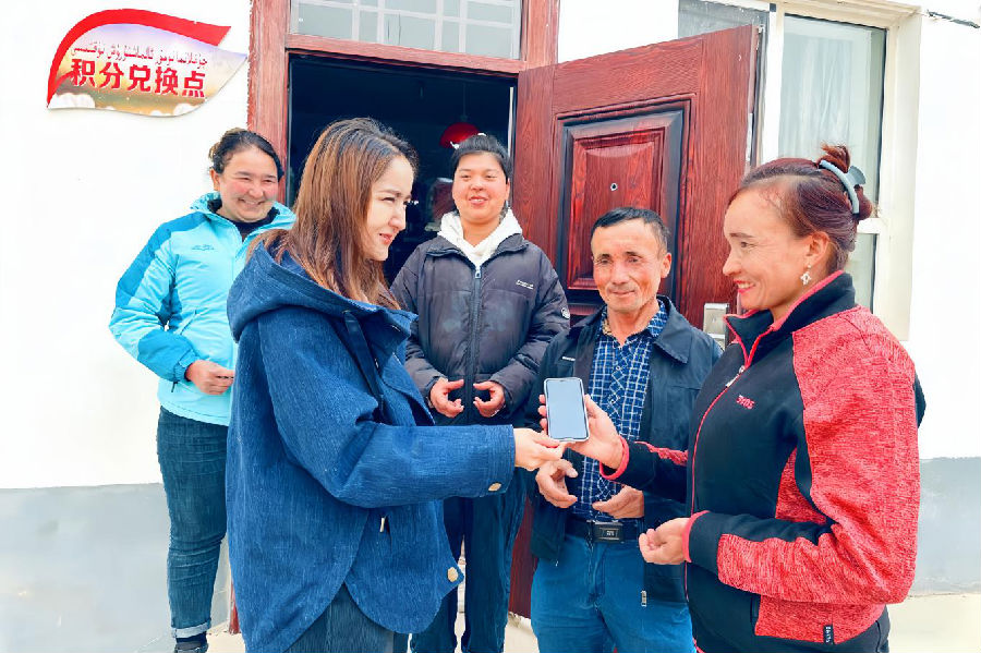 温宿县党员干部在佳木镇阿热勒巴格村“爱心超市”门前给村民兑换积分奖励。（刘雅洁 摄）