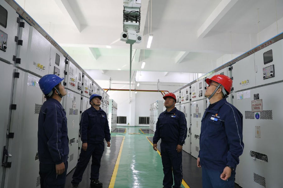张博（右二）与一线技术人员在35KV高压室对核心设备巡检系统稳定性进行观察评估（秦英 摄）