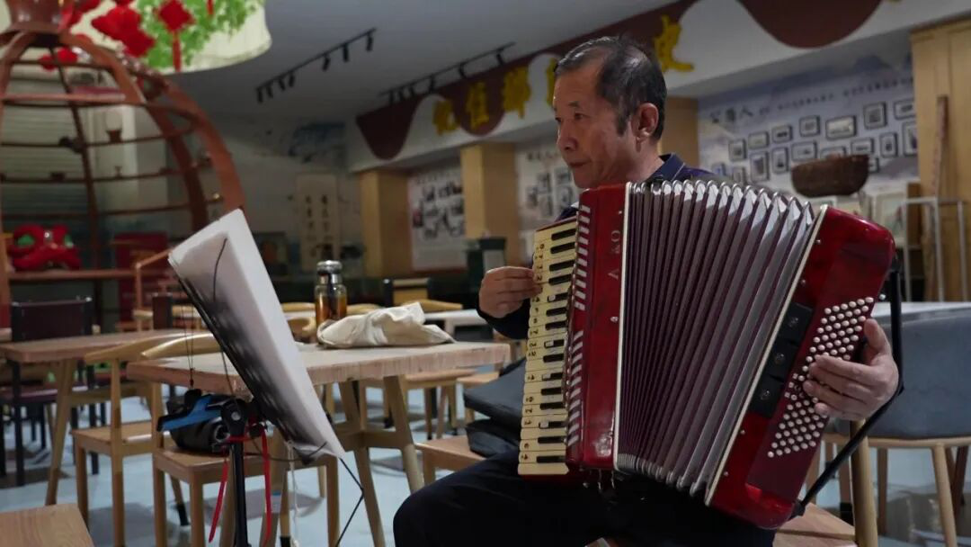 社区居民正在活动室内悠闲地进行手风琴演奏(崔书敏 摄)