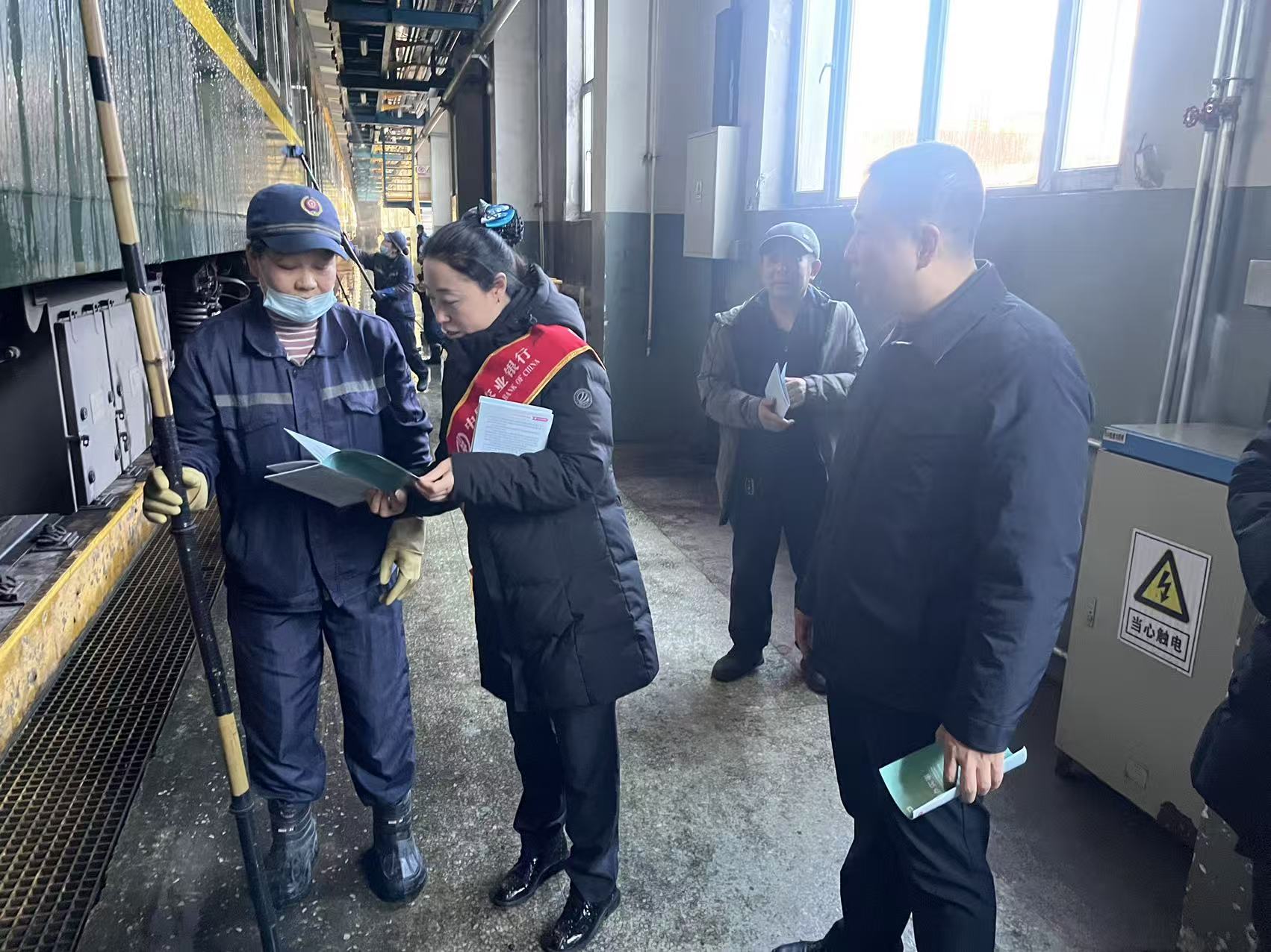 农行工作人员在车间为工人讲解金融知识 (潘明新 摄)