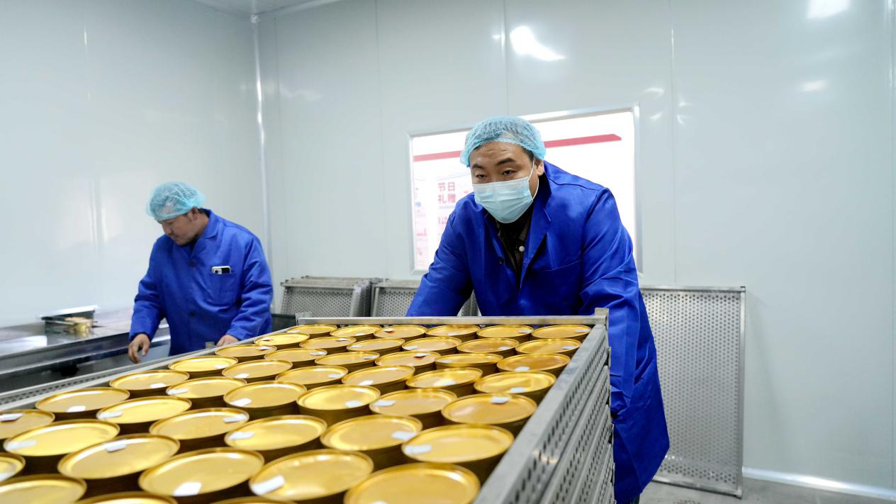 在阿克苏豫闰疆健康食品有限责任公司生产车间,工作人员将灌装好的雪水金盏燕窝炖苹果送至蒸煮釜。(赵新昌 摄)
