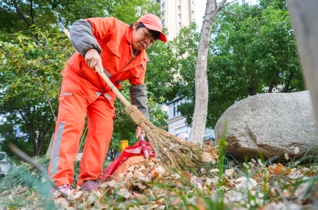 在花亭湖路,环卫工人正在仔细冲刷路面油污和清理落叶(宗雷 摄)