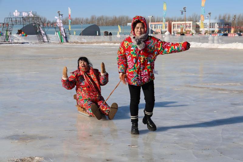 高小玉(左)坐上冰爬犁,重温儿时的快乐回忆。(高冰婵 摄)