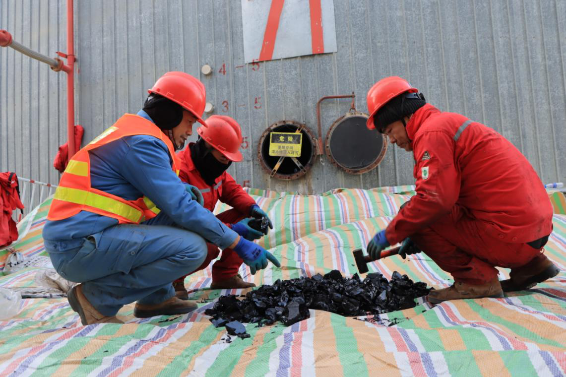 作业人员对硬化沥青进行物理破碎(朱军丽 摄)