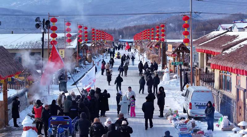 挂满红灯笼的东北雪乡街道上,游人如织,烟火升腾,满是热闹的年味儿。(王佩东 摄)