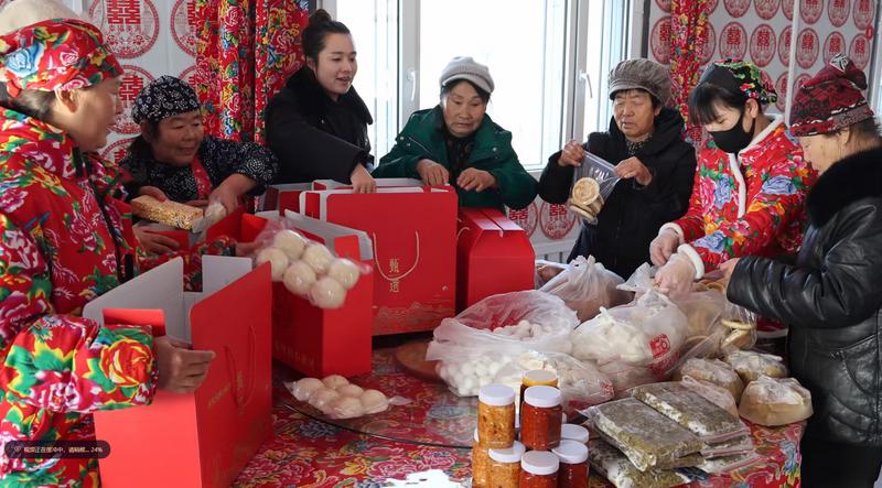 村民们身着特色花棉袄,围坐在一起喜气洋洋地包装年货礼盒。(王佩东 摄)