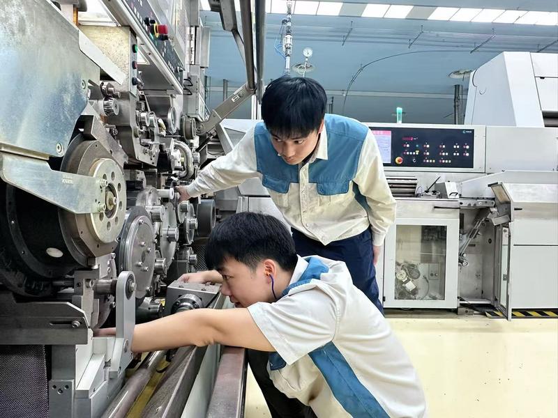 卷包车间青年员工正在抢修高速卷接设备(路美莎 摄)