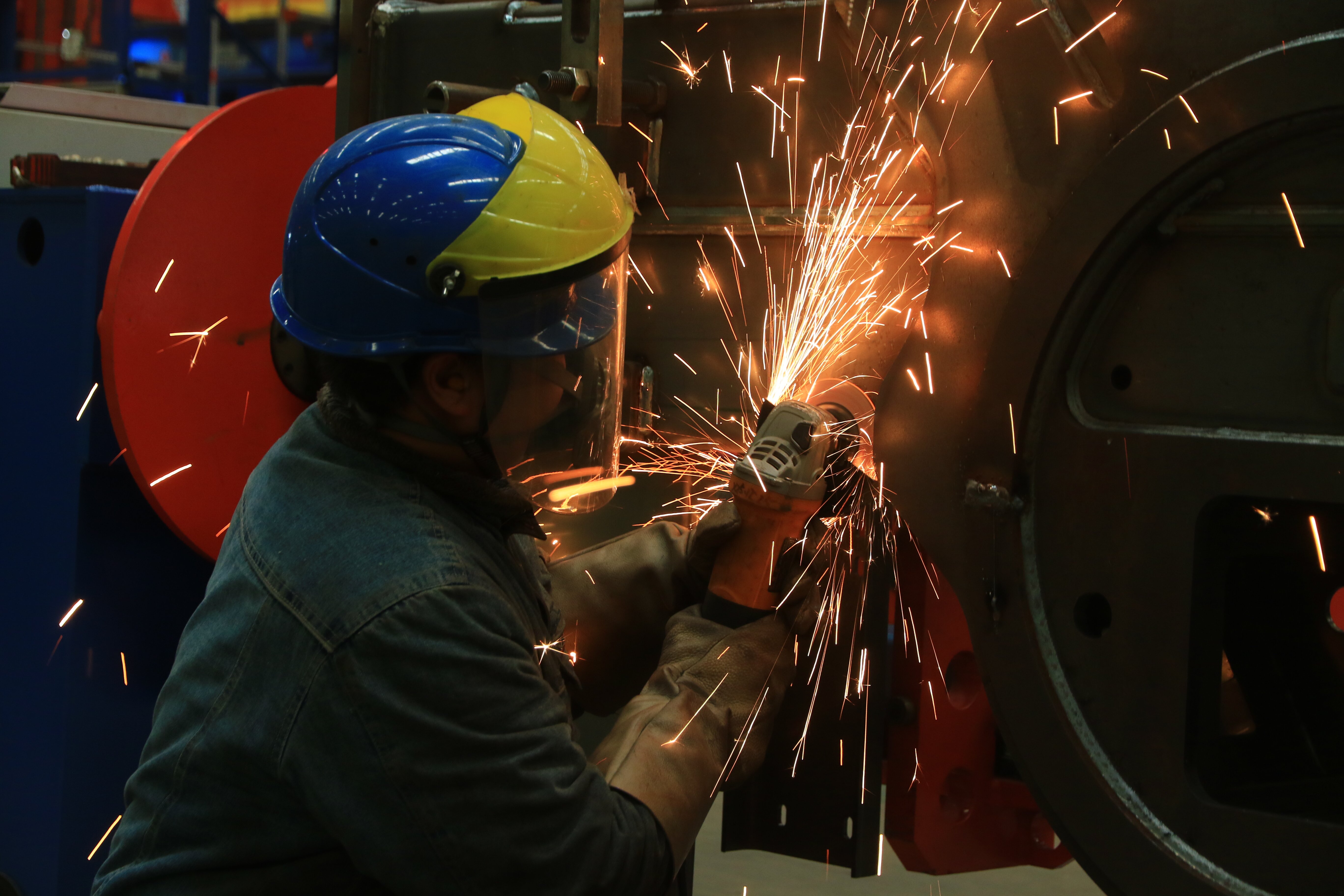 河南骏通车辆有限公司生产车间,工人们用砂轮机打磨零部件上毛刺。(王建栋 摄)
