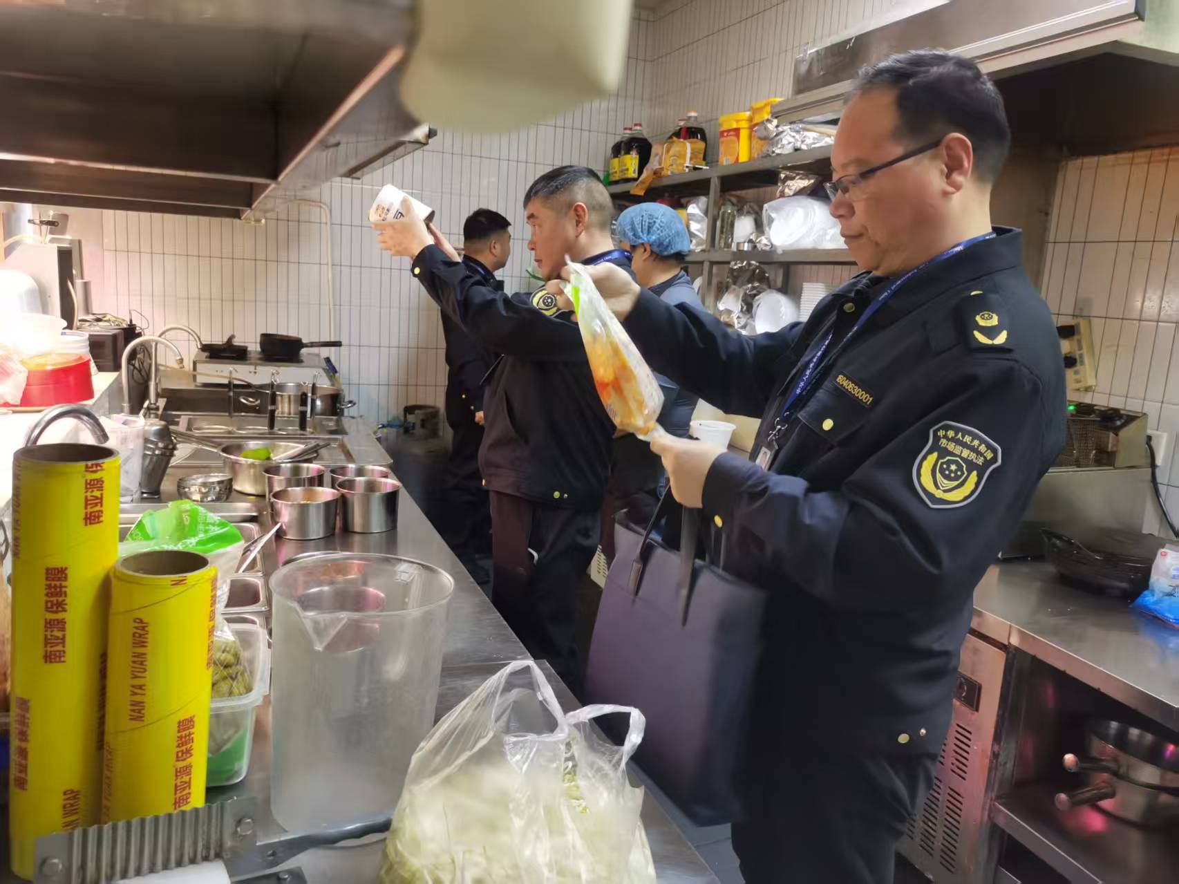 宝丰县市场监督管理局执法人员正在一家饭店后厨检查食材安全(王世超 摄)