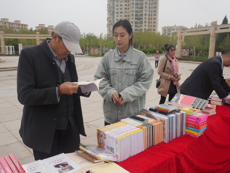 4月20日,温宿县“书香温宿·阅见未来”全民阅读及版权宣传主题活动在启幕,县图书馆设置流动书屋专题阅读区,工作人员给群众热情荐书(张卓凡 摄)