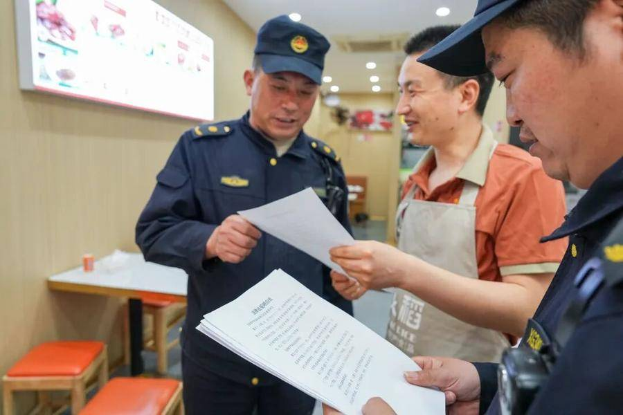 执法队员向商户宣传“门前三包”政策(葛庆钊 摄)