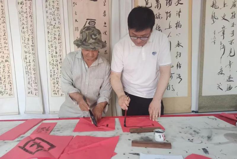 地委宣传部干部在文化大院书法室与村民挥毫泼墨、同书一幅字,以笔墨传情,书写民族团结心声。(殷莉蓉 摄)