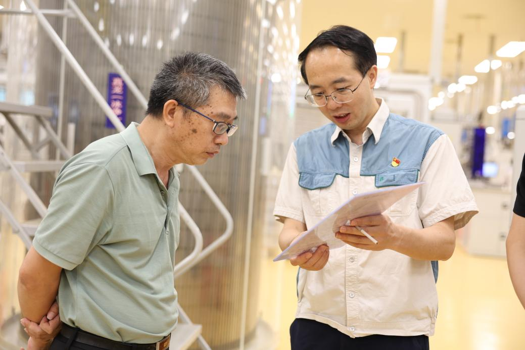 广西中烟技术中心柳州卷烟厂工作站站长范自众(右)与技术中心卷烟材料研究所所长潘连华(左)正在讨论相关工艺标准。(熊科 摄)