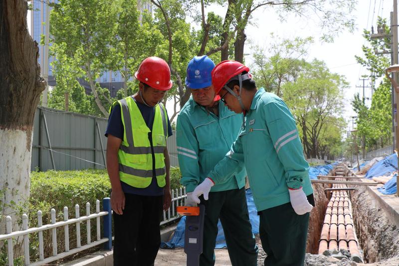 国网阿克苏市供电公司工作人员在解放路10千伏线路“上改下”施工现场,对地下电缆路径进行复核。(邸敏 摄)