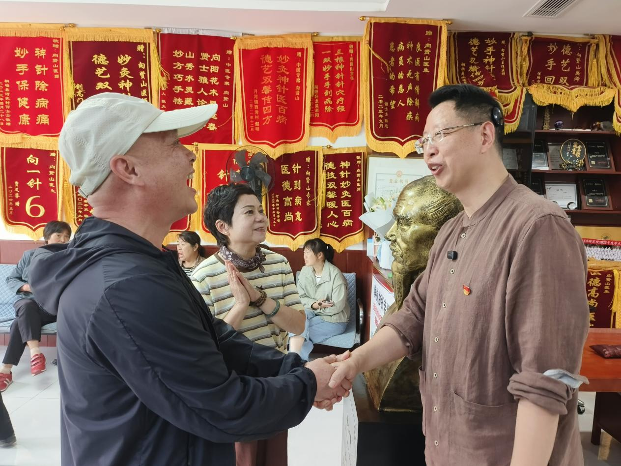 虞爱国夫妇与向贤山(右)握手(牛靖童 摄)
