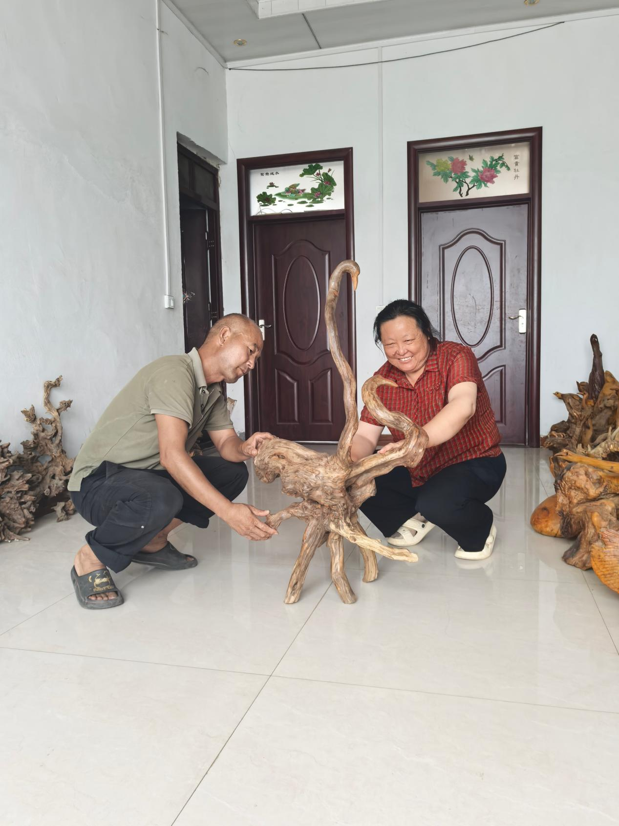 “根艺夫妻”翟猛与张娜在欣赏根艺品《比翼齐飞》(杜福建 摄)