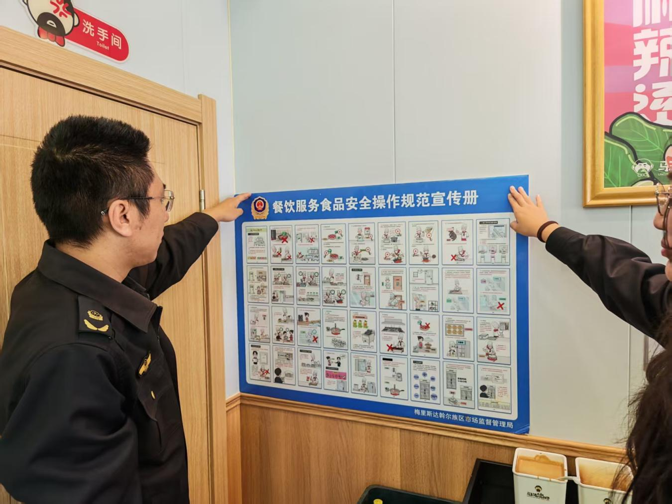 齐齐哈尔市梅里斯达斡尔族区市场监督管理局执法人员逐户对辖区入网餐饮门店开展统一张贴漫画图解(郑雨欣 摄)