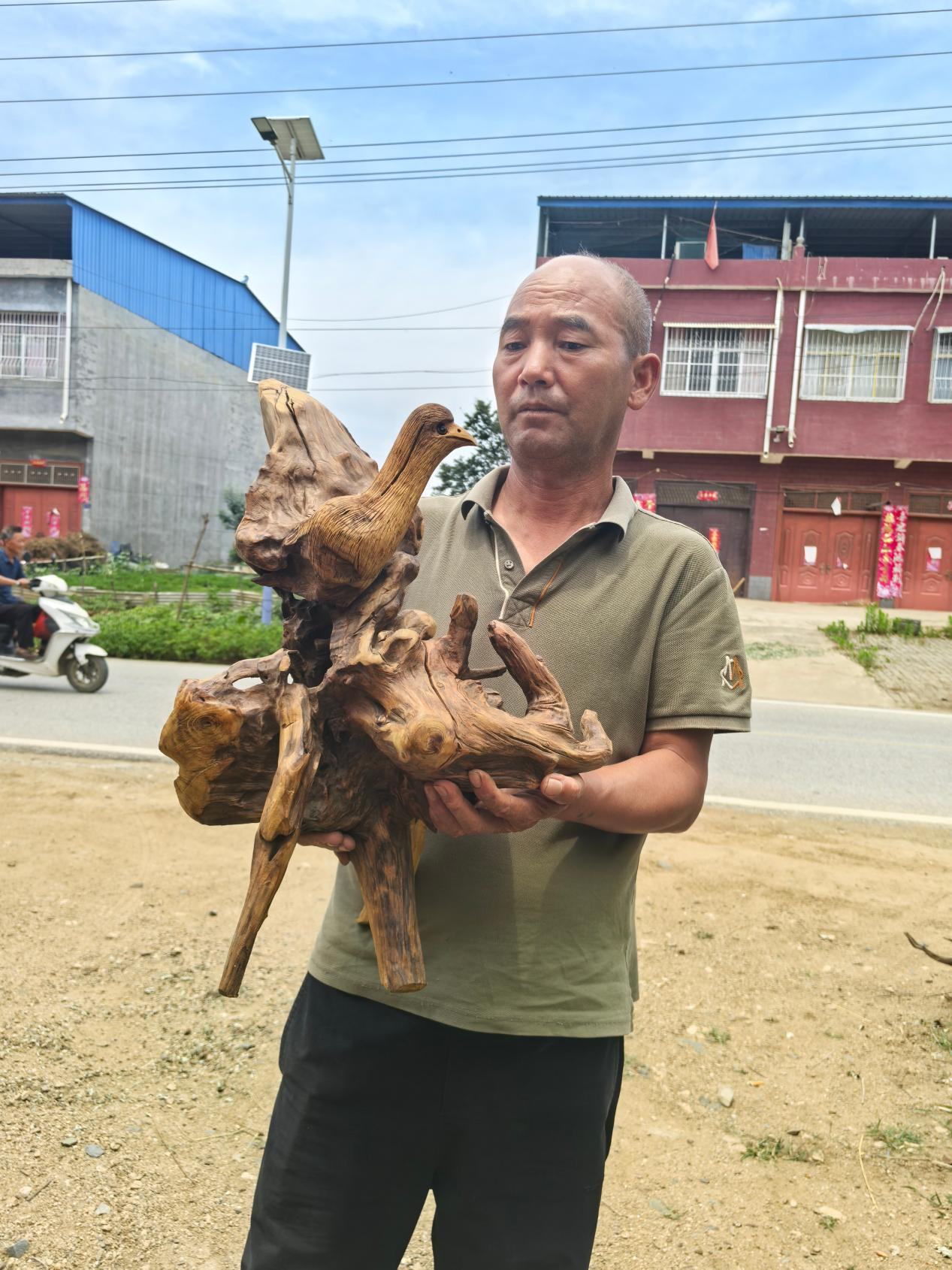 翟猛在欣赏新做成的根艺品(杜福建 摄)