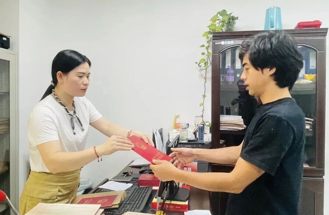 工作人员为群众办结不动产登记并交付证书(陈奇巧 摄)