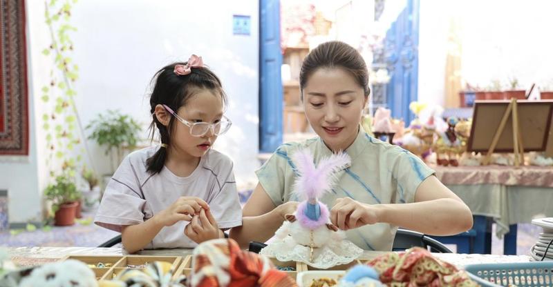 7月21日,马小艳(右)在教孩子作非遗手工。(歹淑丽 摄)