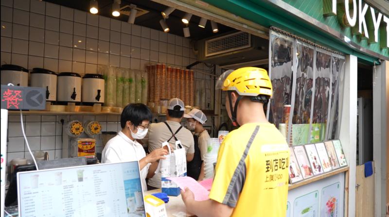 外卖骑手取餐时分享防蚊宣传单,化身街巷“流动宣传员”,将健康提示随餐送达千家万户。(严文丽 摄)
