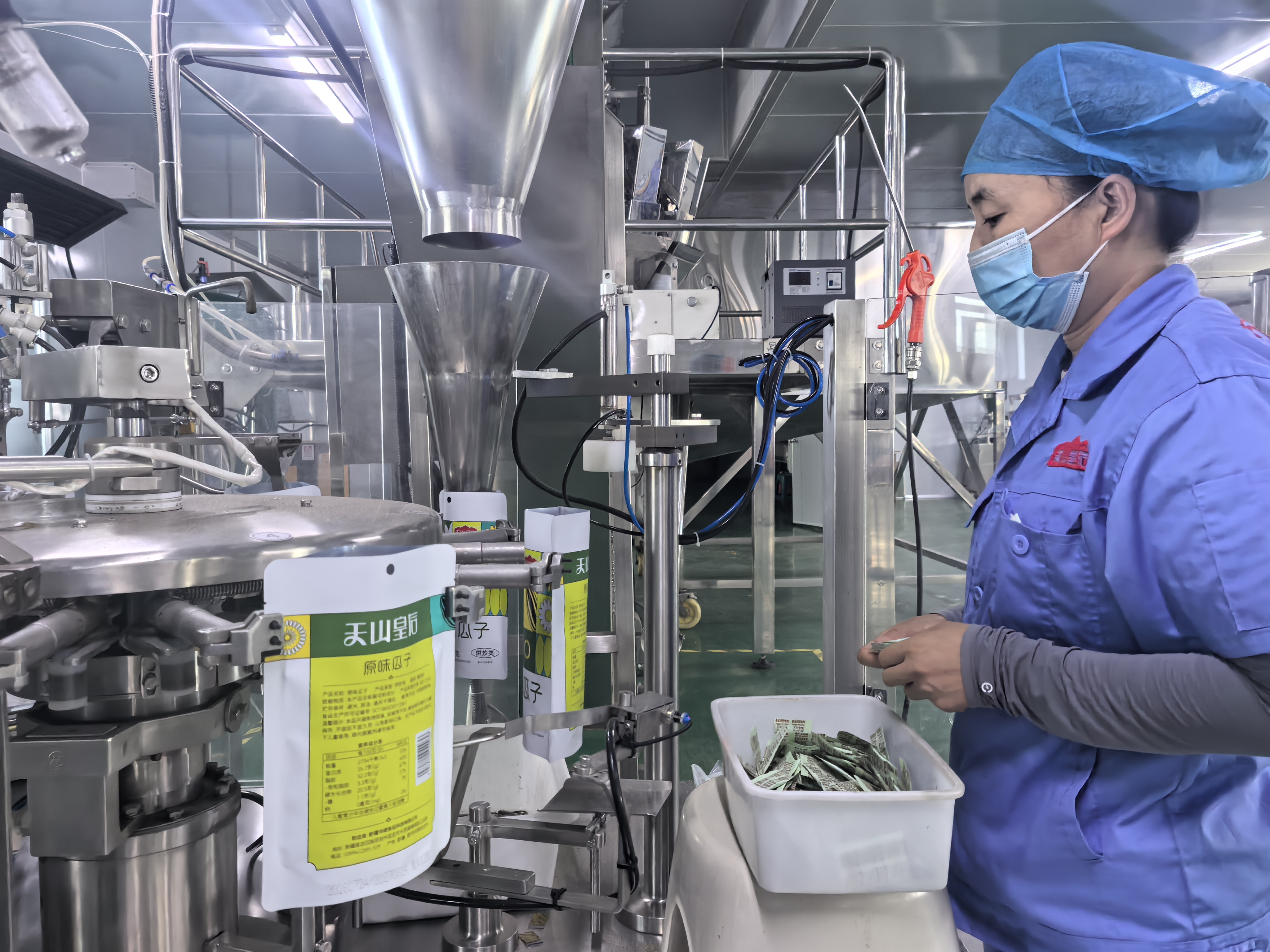新疆华峰食品科技有限公司生产车间工人正在包装休闲食品瓜子。(马月 摄)