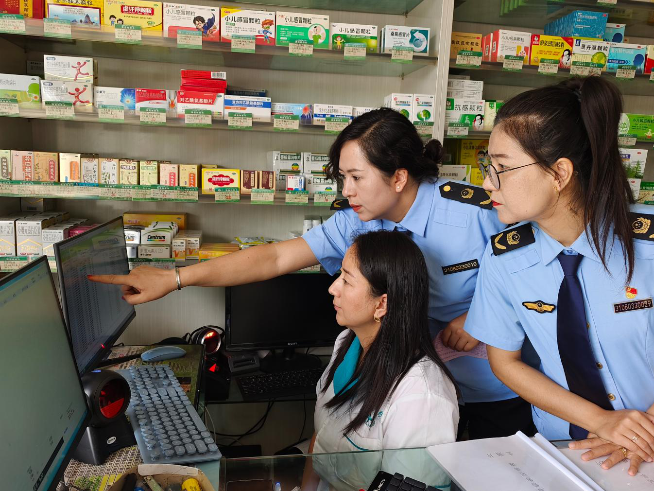执法人员核查药店电子销售台账,运用数字化手段排查监管风险。(李旭洪 摄)